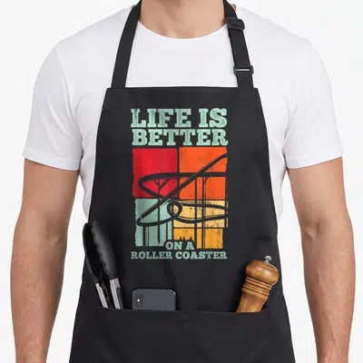 Tablier de cuisine noir avec illustration vintage de montagnes russes et texte Life is Better on a Roller Coaster en pastel et orange.