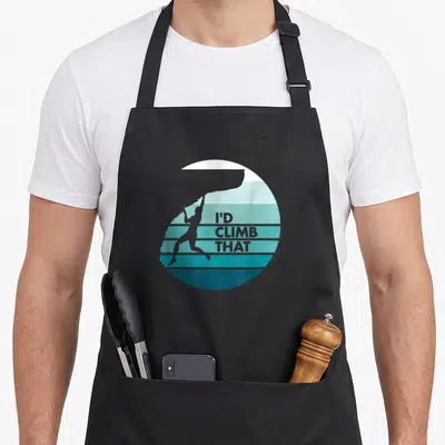 Tablier de cuisine noir avec un grimpeur silhouetté et le texte I'd Climb That sur fond de bandes horizontales turquoise.