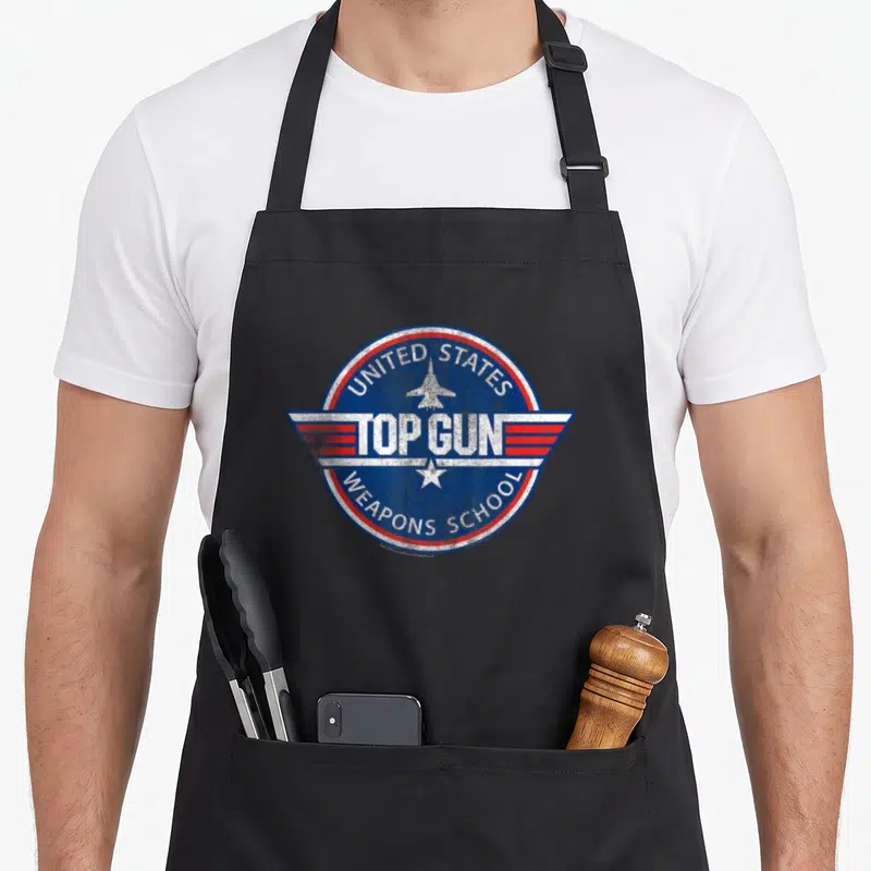 Tablier de cuisine noir avec insigne circulaire Top Gun United States Weapons School bleu et rouge.