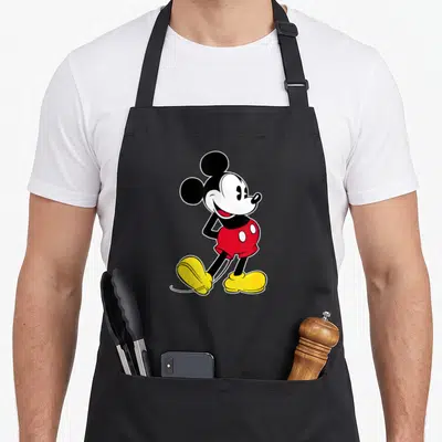 Tablier de cuisine noir avec Mickey Mouse en pose classique rouge et jaune souriant