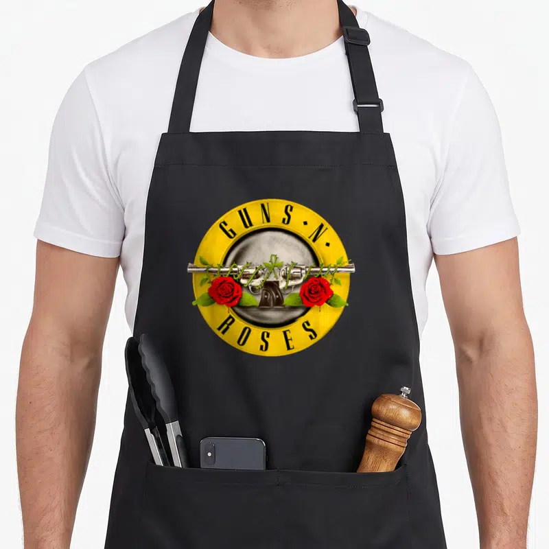 Tablier de cuisine noir avec logo Guns N Roses, revolver et roses rouges sur fond jaune circulaire.