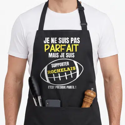Tablier de cuisine noir avec texte blanc et jaune et illustration de ballon de rugby stylisé au centre du vêtement.