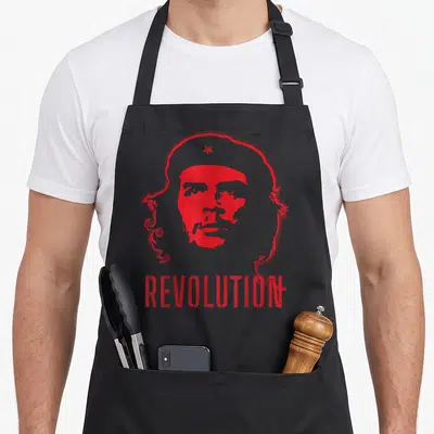 Tablier de cuisine noir avec portrait rouge stylisé et le mot REVOLUTION imprimé en bas.