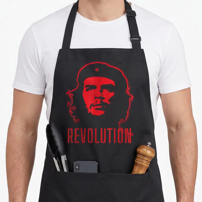 Tablier de cuisine noir avec portrait rouge stylisé et le mot REVOLUTION imprimé en bas.