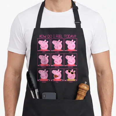 Tablier de cuisine noir avec grille de neuf visages de Peppa Pig illustrant des émotions comme happy, angry ou hungry.