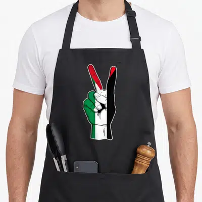 Tablier de cuisine noir avec une main dessinant la paix aux couleurs du drapeau palestinien.