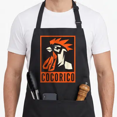 Tablier de cuisine noir avec illustration stylisée d'un coq orange et texte Cocorico en bas.