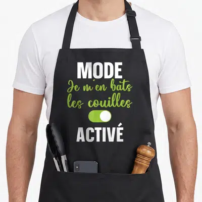 Tablier de cuisine noir avec le texte Je m'en bats les couilles Mode activé en vert et blanc.