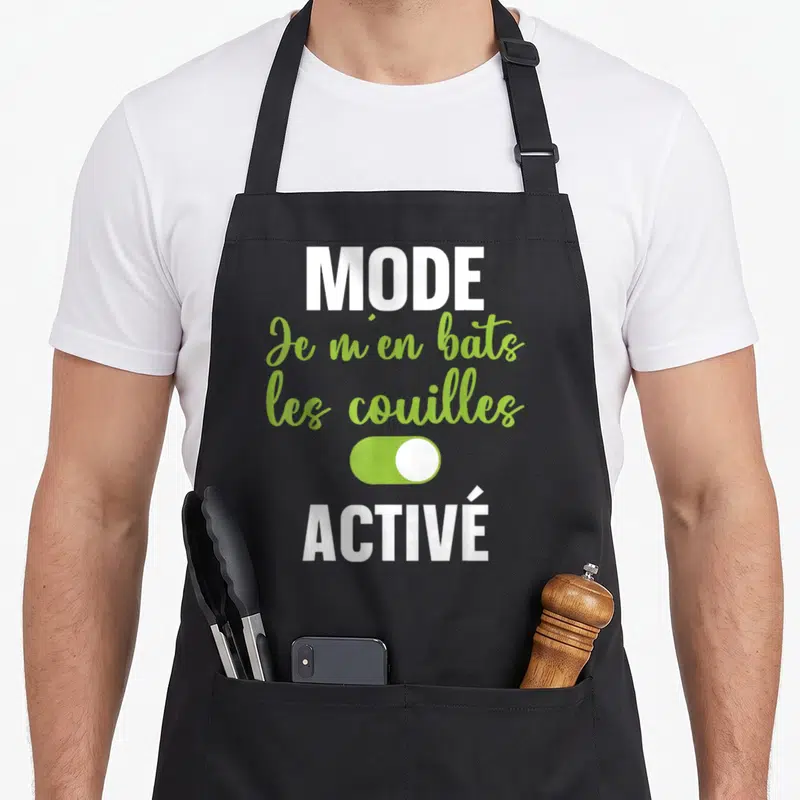 Tablier de cuisine noir avec le texte Je m'en bats les couilles Mode activé en vert et blanc.