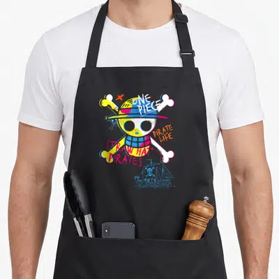 Tablier de cuisine noir avec un crâne aux os croisés et le texte Straw Hat Pirates en lettres colorées.