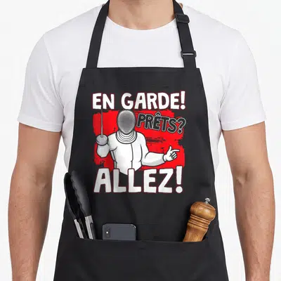 Tablier de cuisine noir avec illustration d'un escrimeur et texte En Garde Prêts Allez sur fond rouge.