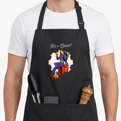 Tablier de cuisine noir avec illustration d'une femme en combinaison bleue assise sur une caisse Nuka Cola