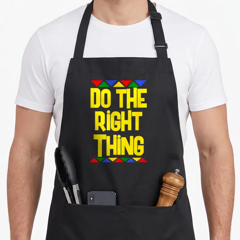 Tablier de cuisine noir avec inscription jaune Do The Right Thing encadrée de triangles rouges verts bleus et jaunes.