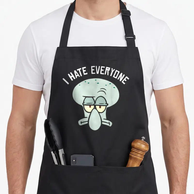 Tablier de cuisine noir avec le visage de Squidward et l'inscription I HATE EVERYONE en lettres blanches.