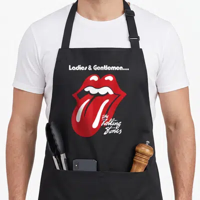 Tablier de cuisine noir avec les lèvres rouges des Rolling Stones et le texte Ladies & Gentlemen imprimé en blanc.
