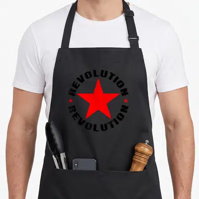 Tablier de cuisine noir avec étoile rouge centrale entourée du mot révolution en cercle noir style pochoir usé.