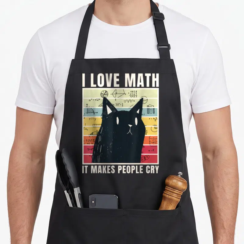 Tablier de cuisine noir avec illustration de chat noir sur fond de formules mathématiques colorées et texte en anglais.