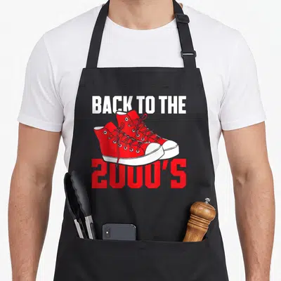 Tablier de cuisine noir avec illustration de sneakers rouges et texte Back to the 2000's en blanc et rouge.