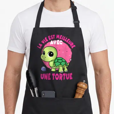 Tablier de cuisine noir avec une tortue verte et le texte la vie est meilleure avec une tortue sur fond rose.