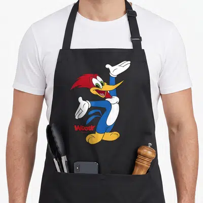 Tablier de cuisine noir avec Woody Woodpecker en train de danser les bras levés et le nom Woody en rouge en bas à gauche.
