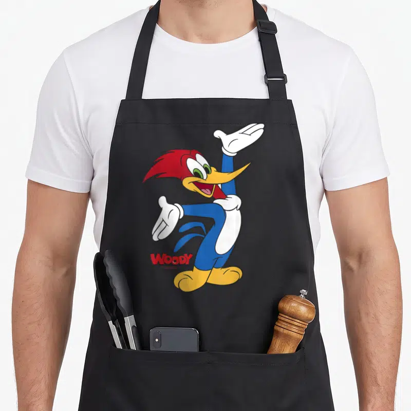 Tablier de cuisine noir avec Woody Woodpecker en train de danser les bras levés et le nom Woody en rouge en bas à gauche.
