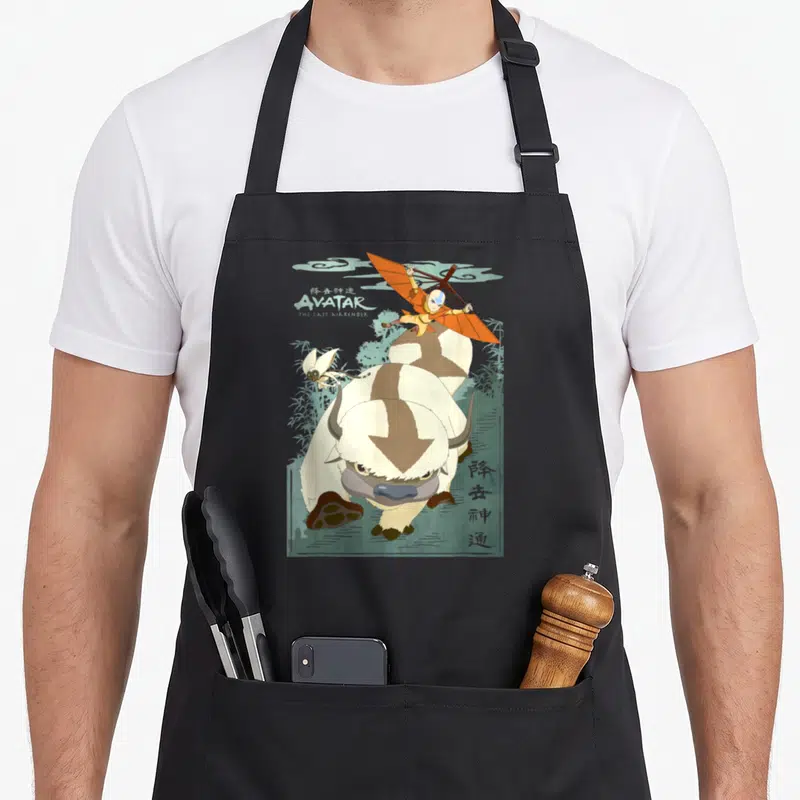 Tablier de cuisine noir avec illustration colorée d'Aang sur Appa le bison volant et Momo la créature ailée.