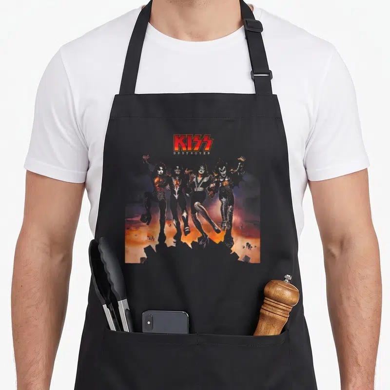 Tablier de cuisine noir avec les quatre silhouettes de l'album Destroyer de Kiss sur fond orangé et fumé.