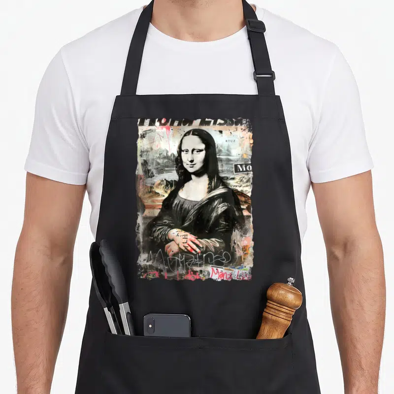 Tablier de cuisine noir avec une version graffiti de la Joconde et des tags artistiques colorés.