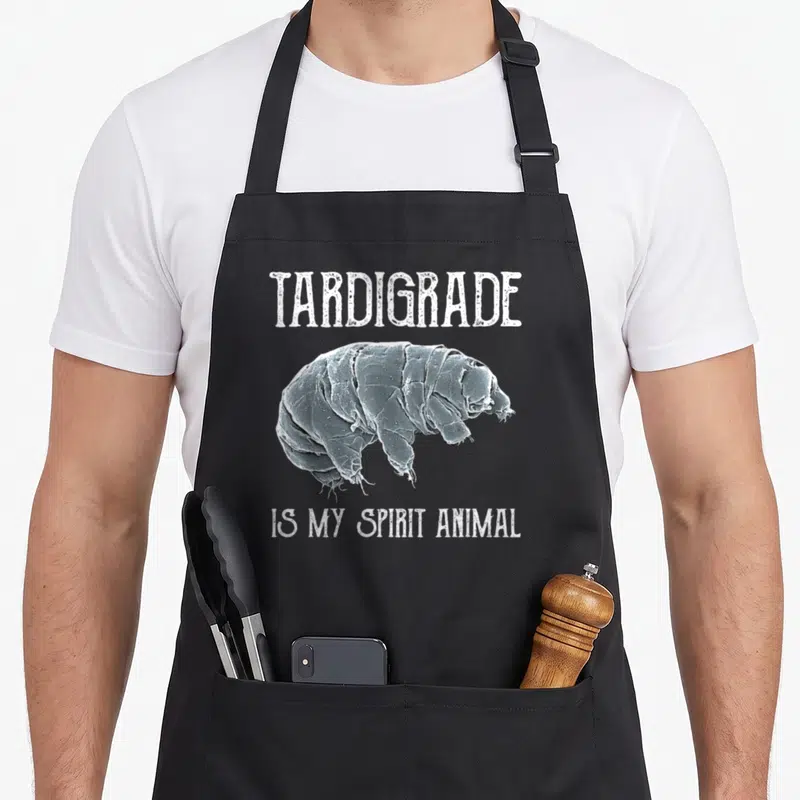 Tablier de cuisine noir avec illustration détaillée d'un tardigrade et texte blanc en typographie usée.