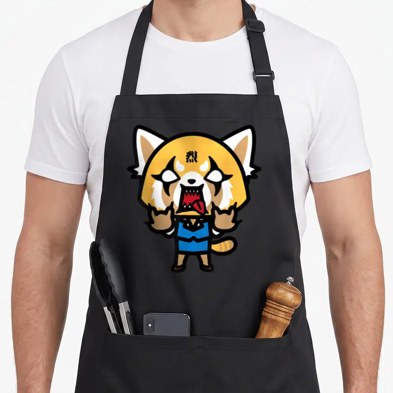 Tablier de cuisine noir avec illustration colorée d'Aggretsuko en train de crier et de faire des signes de cornes.