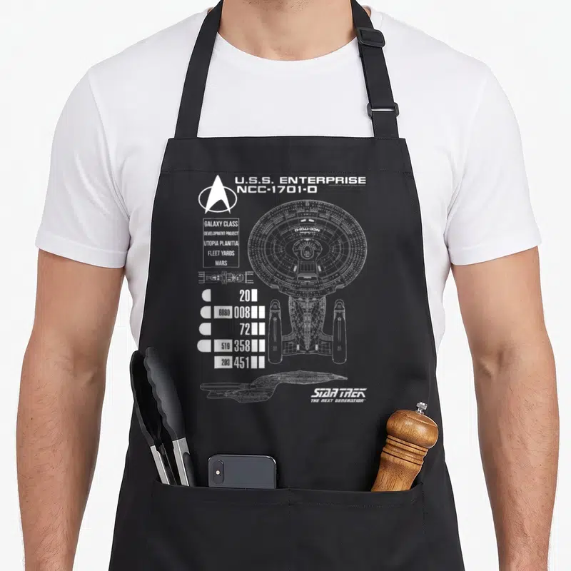 Tablier de cuisine noir avec le plan technique blanc de l'U.S.S. Enterprise NCC-1701-D et le logo Star Trek.