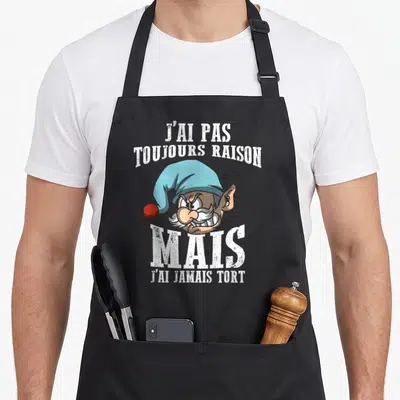 Tablier de cuisine noir avec illustration d'un gnome aux dents serrées et texte blanc humoristique sur le devant.