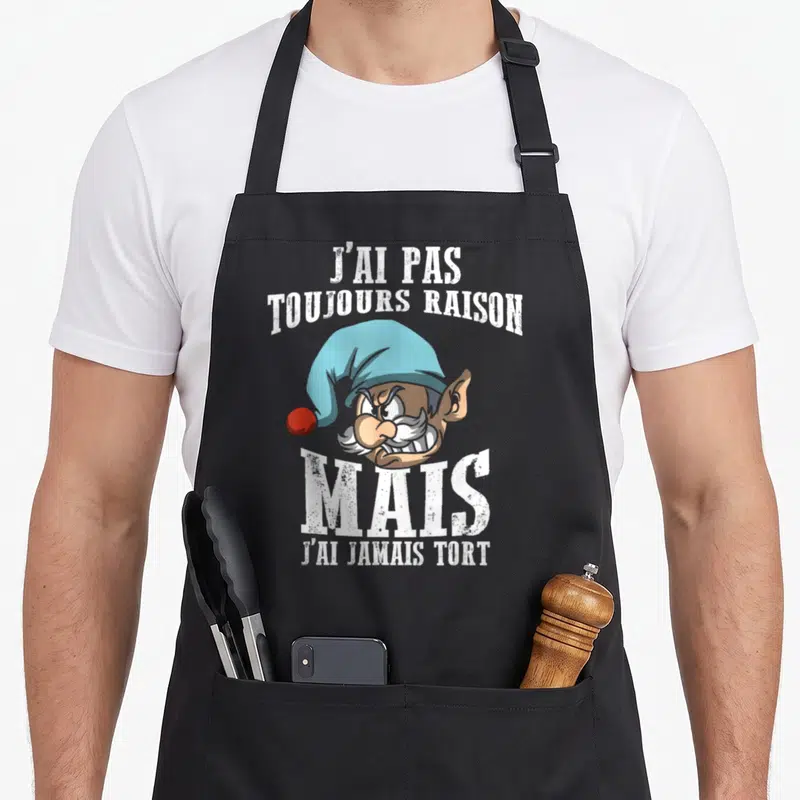 Tablier de cuisine noir avec illustration d'un gnome aux dents serrées et texte blanc humoristique sur le devant.