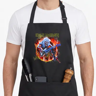 Tablier de cuisine noir avec Eddie aux flammes jouant d'une basse bleue sous le logo jaune.