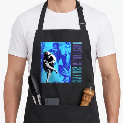 Tablier de cuisine noir avec illustration bleue d'une silhouette et texte vertical Guns N' Roses Utilisez Votre Illusion II.
