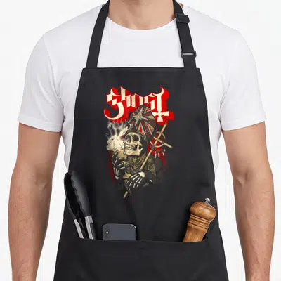 Tablier de cuisine noir avec illustration d'un crâne en mitre tenant un calice et une crosse.