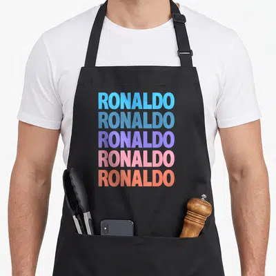 Tablier de cuisine noir avec le texte RONALDO répété en lettres majuscules aux couleurs dégradées.