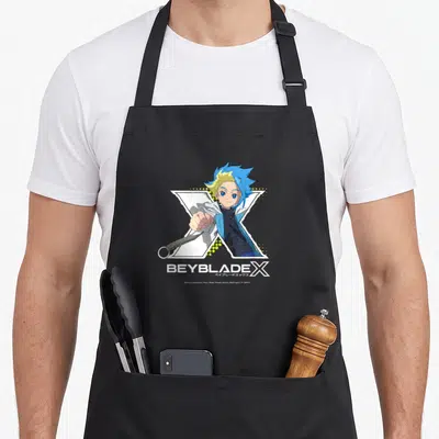 Tablier de cuisine noir avec le personnage Jaxon Cross et le logo Beyblade X en couleurs vives sur fond blanc.