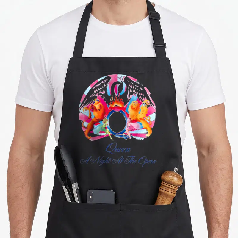 Tablier de cuisine noir avec illustration colorée de lion, aigle et fées sous le nom Queen en écriture bleue.