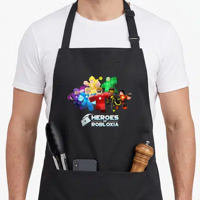 Tablier de cuisine noir avec six personnages colorés et le logo Heroes of Robloxia imprimés au centre.