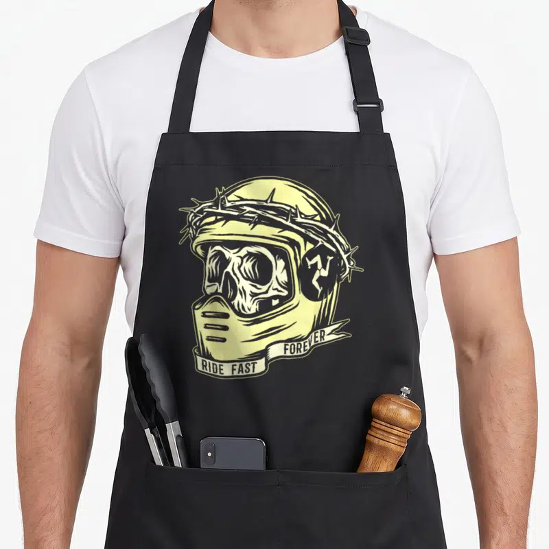 Tablier de cuisine noir avec illustration casque de moto jaune et blanc, couronne d'épines et texte Ride Fast Forever sur banderole.