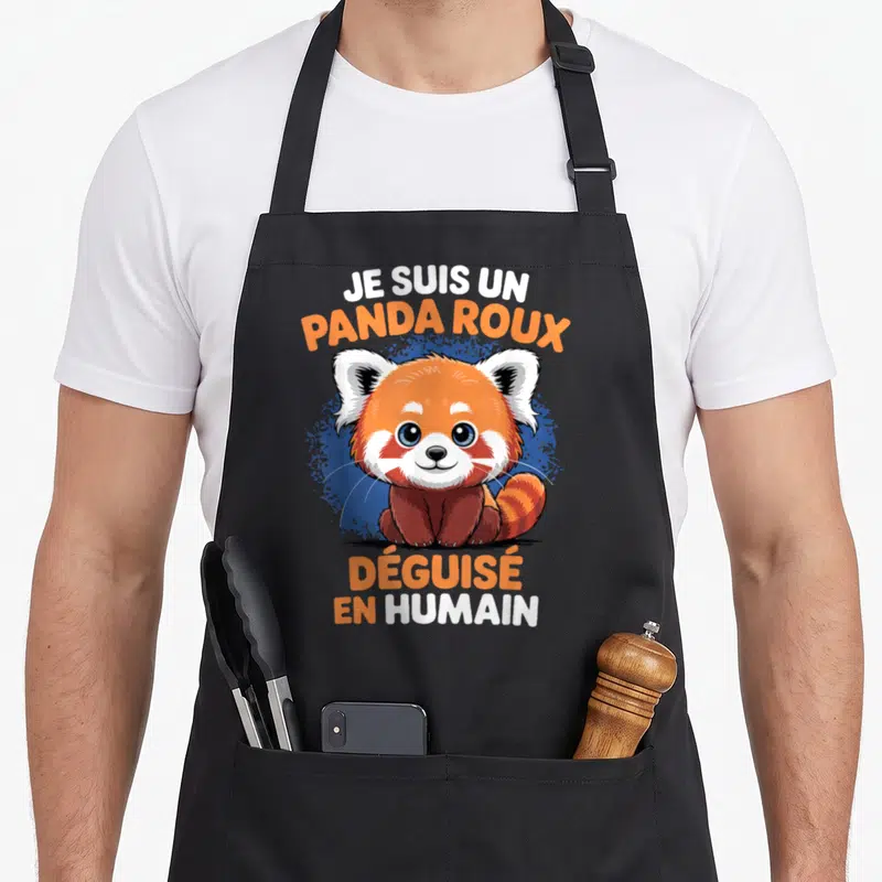 Tablier de cuisine noir avec illustration d'un panda roux souriant et texte humoristique en orange et blanc.