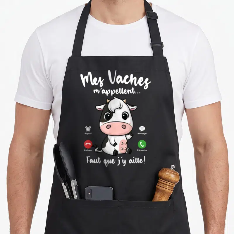 Tablier de cuisine noir avec une vache dessinée et les mots Mes Vaches m'appellent Faut que j'y aille.