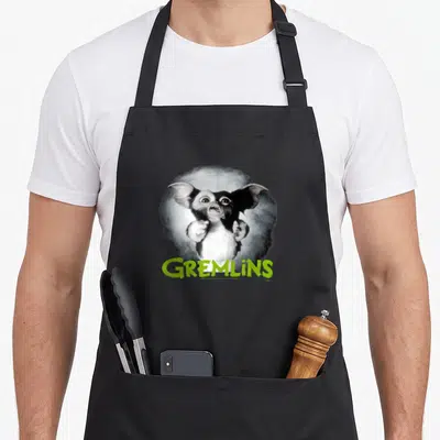Tablier de cuisine noir avec un gremlin effrayé et le mot Gremlins en vert lime