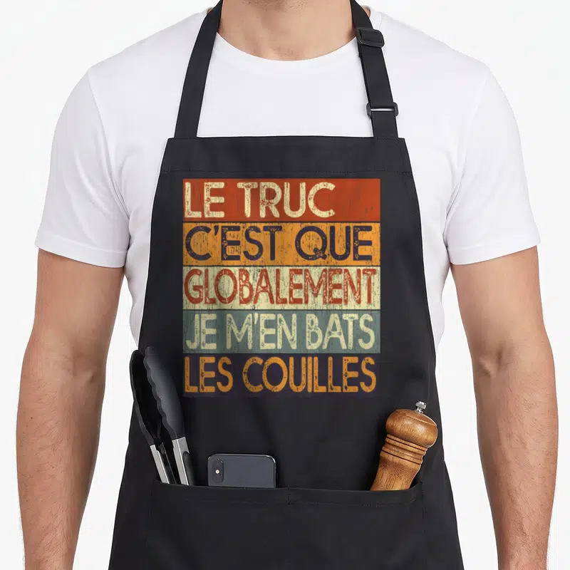 Tablier de cuisine noir avec inscription Le Truc C'est Que Globalement Je M'en Bats Les Couilles sur fond de bandes colorées vintage.