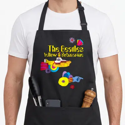 Tablier de cuisine noir avec une sous-marine jaune, une main bleue et le texte The Beatles Yellow Submarine.