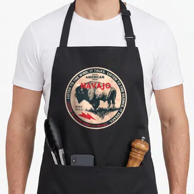 Tablier de cuisine noir avec illustration circulaire d'un bison Navajo et texte en anglais.