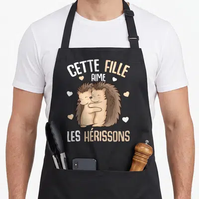Tablier de cuisine noir avec deux hérissons marron s'enlaçant sous le texte Cette fille aime les hérissons entouré de petits cœurs blancs et beige.
