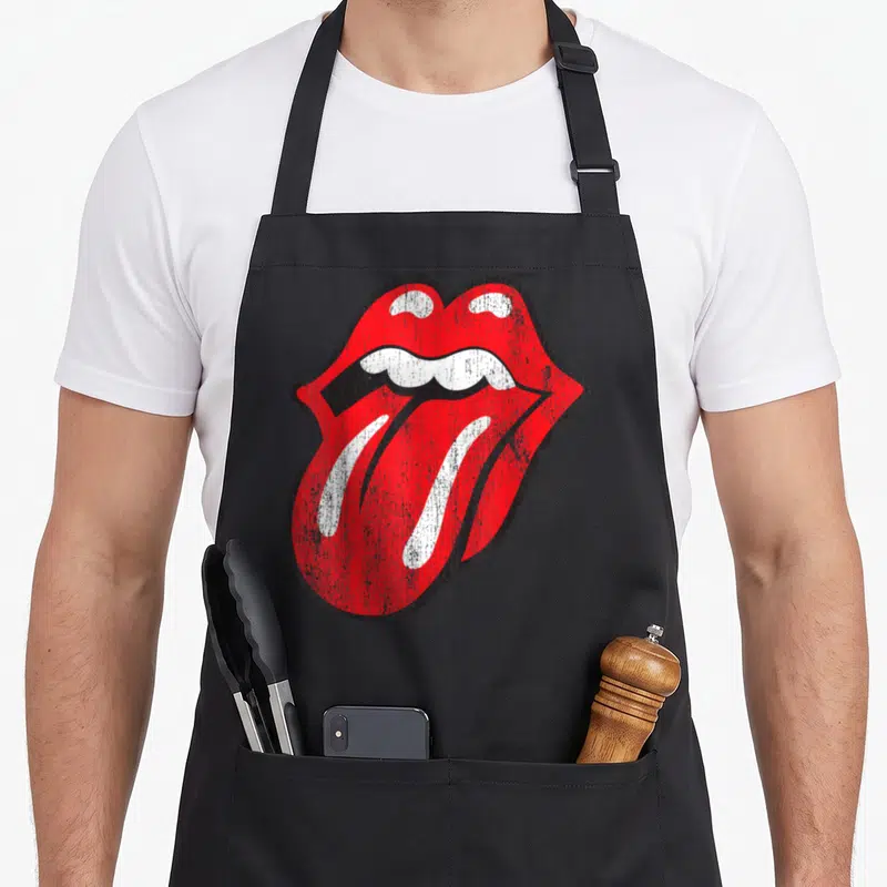 Tablier de cuisine noir avec le logo d'une bouche et d'une langue rouge vieillie au centre.