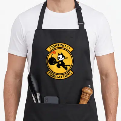 Tablier de cuisine noir avec le logo rond Fighting 31 Tomcatters montrant un chat noir portant une bombe.